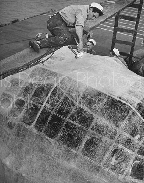 US naval vessal  being sprayed with weather proofing plastic while docked in a storage depot waiting for reuse.