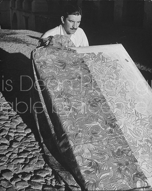 A man working with hand blocked fabrics made by tillets.