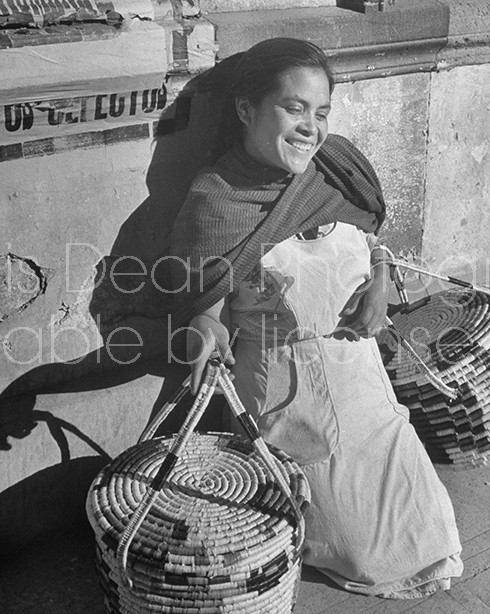 A young woman holding baskets and resting at the market.