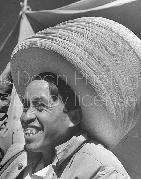 A hat vendor wearing a large stack of hats.