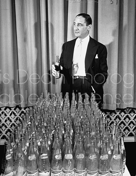 Pres. Pepsi Cola Co. Walter S. Mack Jr. standing behind empty Pepsi bottles.