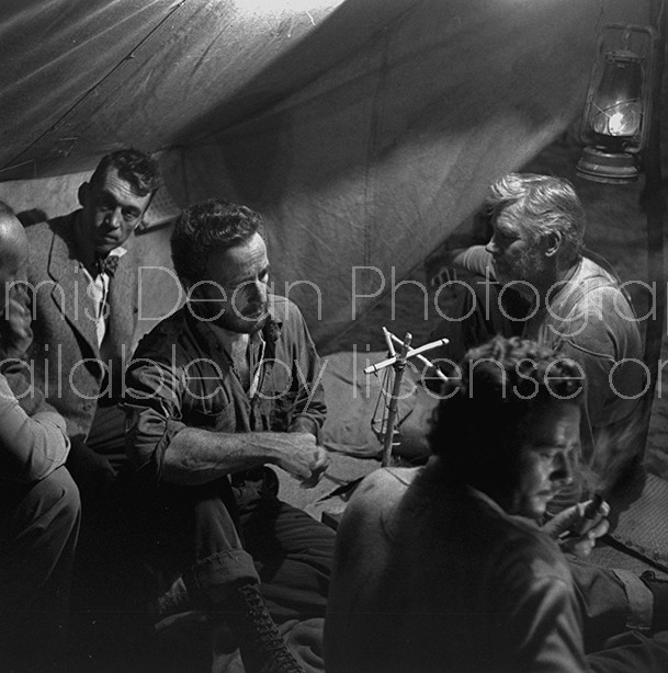 Director of "The Treasure of the Sierra Madre" John Huston (2L) with the film's actors Humphrey Bogart (C) and his father Walter Huston (R) and two unident. others as they talk inside of lamplit tent.