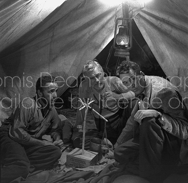 Director of "The Treasure of the Sierra Madre" John Huston (R) with the film's actors Humphrey Bogart (L) and his father Walter Huston (C), as they talk inside of lamplit tent while testing handmade scale.