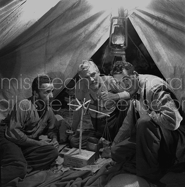 Director of "The Treasure of the Sierra Madre" John Huston (R) with the film's actors Humphrey Bogart (L) and his father Walter Huston (C), as they talk inside of lamplit tent while testing handmade scale.