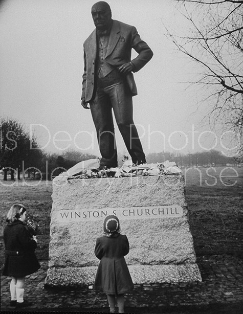 A 9-ft. statue of Sir Winston Churchill, is visited by young girls mourning his death.