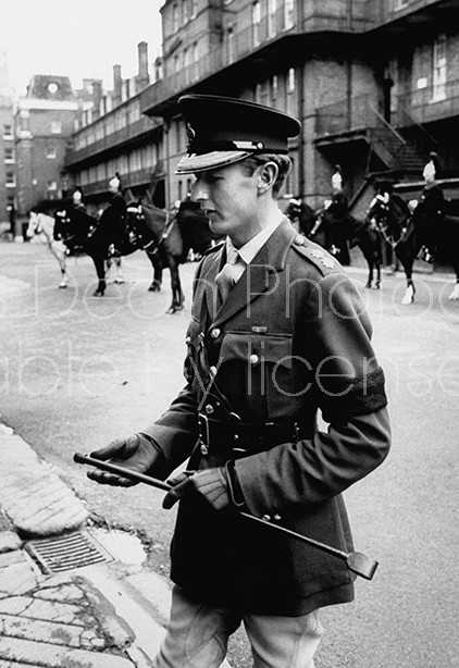 Army soldier reading details of John F. Kennedy's assassination outside of US Embassy in London.