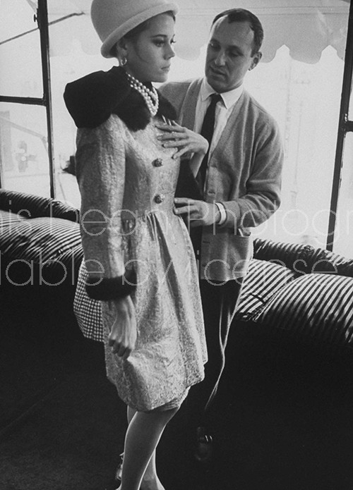 Actress Jane Fonda trying on a brocade coat as designer Louis Feraud looks on.