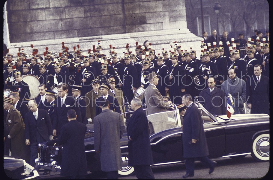 French President Charles de Gaulle standing in an open car driving up the Champs Elysees to the Arc de Triomphe ceremony on his Inauguration day.