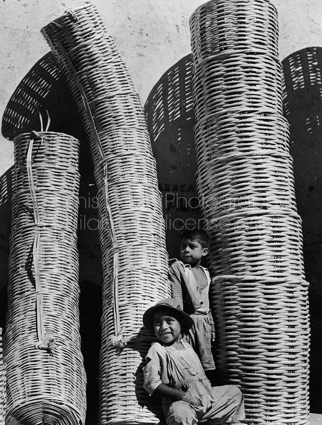 Two children standing amongst stacks of baskets in Mexico.