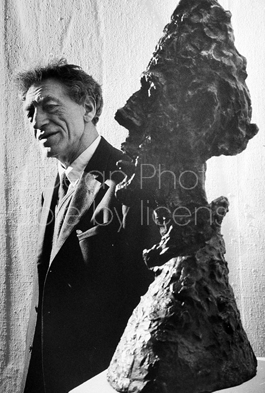 Swiss sculptor Alberto Giacometti w. one of his characteristically stylized heads, at museum.