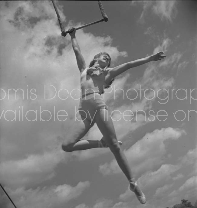 CIRCUS ACROBAT POSING FROM TRAPEZE 