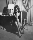 Actress Claudine Auger in sleeveless dress w. low-cut neckline, relaxing in Louis XVI-style chair in her elegant apt.
