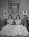 Debutantes Mary & Debbie Love posing on sofa in identical ball gowns on day of their debut into society.