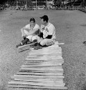 Pittsburgh Pirates players (L-R) Ralph Kiner & Hank Greenberg sitting next to a row of baseball bats during spring training.