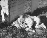 A girl posing next to a grave.