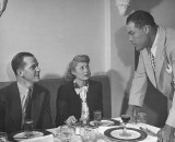 Boxer Joe Louis talking with patrons at his restaurant.