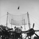 Pilot ejector test, explosive charge sends pilot's seat looping from cockpit of bomber into large net.