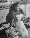 A young woman holding baskets and resting at the market.