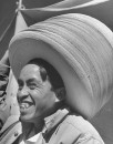 A hat vendor wearing a large stack of hats.