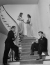 Co-ed girls wearing formal dresses while their dates are wearing formal tuxedoes with boots.