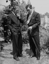 Actors Errol Flynn (L) and Anthony Quinn smoking cigarettes.