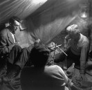 Director of "The Treasure of the Sierra Madre" John Huston (L) with the film's actors Humphrey Bogart (C, lying down) and his father Walter Huston as they talk inside of lamplit tent.