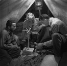 Director of "The Treasure of the Sierra Madre" John Huston (R) with the film's actors Humphrey Bogart (L) and his father Walter Huston (C), as they talk inside of lamplit tent while testing handmade scale.