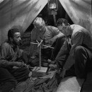 Director of "The Treasure of the Sierra Madre" John Huston (R) with the film's actors Humphrey Bogart (L) and his father Walter Huston (C), as they talk inside of lamplit tent while testing handmade scale.