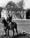 Actor/Director John Huston, sitting on top of his horse in front of his large home.