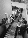 Restaurant staff incl. chefs & waiters carrying trays of food as they ride up & down on the escalator from the 2-story kitchen of the Rotterdam Hilton Hotel.