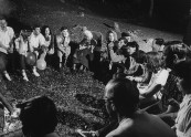 Actress Margaret Rutherford telling ghost stories to youth around a campfire.