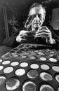 British mystery writer Ian Fleming inspecting old Brazilian coins, magnifying glass ready.
