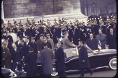 French President Charles de Gaulle standing in an open car driving up the Champs Elysees to the Arc de Triomphe ceremony on his Inauguration day.