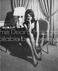 Actress Claudine Auger in sleeveless dress w. low-cut neckline, relaxing in Louis XVI-style chair in her elegant apt.