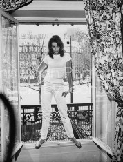 Actress Claudine Auger in ribbed t-shirt & tight pants, posing in large window of her elegant apt. w. street in bkgrd.
