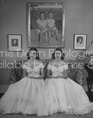 Debutantes Mary & Debbie Love posing on sofa in identical ball gowns on day of their debut into society.