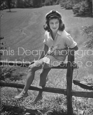 Debutante Debbie Love sitting on fence railing.