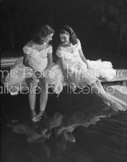 Debutantes Mary & Debbie Love posing on next to pool in identical ball gowns on day of their debut into society.