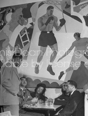 Boxer Joe Louis talking with patrons at his restaurant.