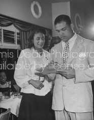 Boxer Joe Louis talking with patrons at his restaurant.