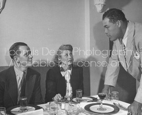 Boxer Joe Louis talking with patrons at his restaurant.