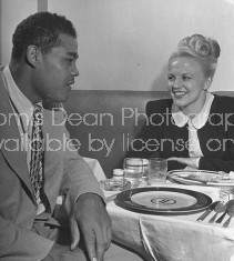 Boxer Joe Louis talking with patron at his restaurant.