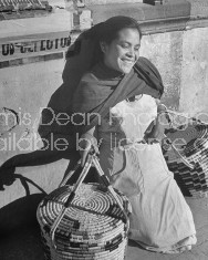 A young woman holding baskets and resting at the market.