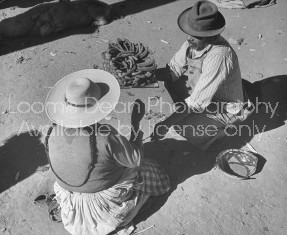 A man and woman crouching in the marketplace together.