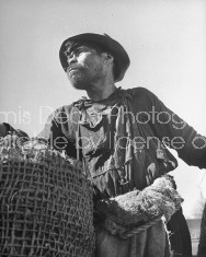 A man standing next to a large basket in the market.