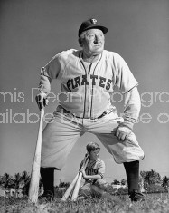 Pirates baseball player Honus Wagner standing and holding baseball bat.