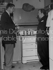 (L-R) Actors Vincent Price and Thomas Mitchell talking in a kitchen.