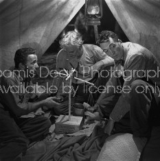 Director of "The Treasure of the Sierra Madre" John Huston (R) with the film's actors Humphrey Bogart (L) and his father Walter Huston (C), as they talk inside of lamplit tent while testing handmade scale.