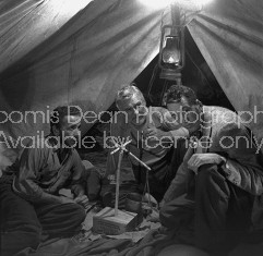 Director of "The Treasure of the Sierra Madre" John Huston (R) with the film's actors Humphrey Bogart (L) and his father Walter Huston (C), as they talk inside of lamplit tent while testing handmade scale.