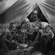 Director of "The Treasure of the Sierra Madre" John Huston (R) with the film's actors Humphrey Bogart (L) and his father Walter Huston (C), as they talk inside of lamplit tent while testing handmade scale.